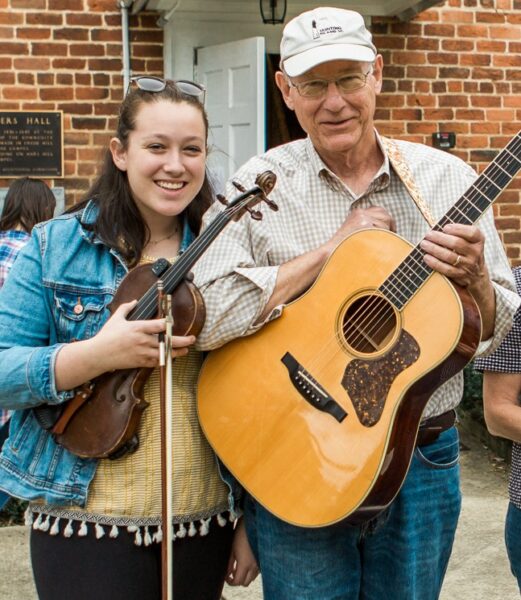 Young woman holding fiddle and older man holding guitar