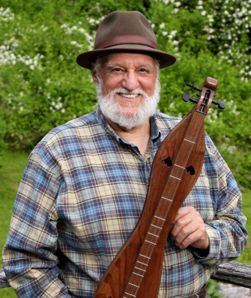 Man smiling and holding dulcimer. 