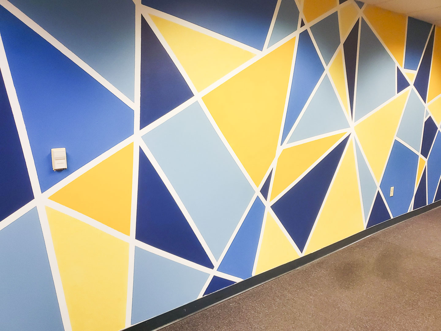 Mindspace mural wall with geometric shapes painted in tones of blue and yellow