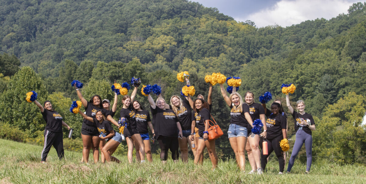 Group of cheerleaders waving pom poms in a field