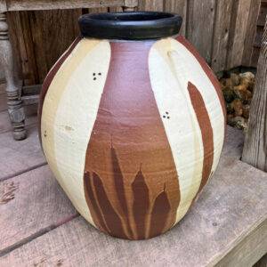 A ceramic white, brown and tan pot sits on a porch