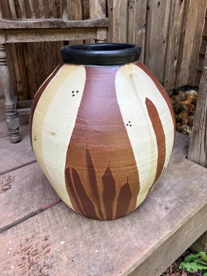 A ceramic white, brown and tan pot sits on a porch