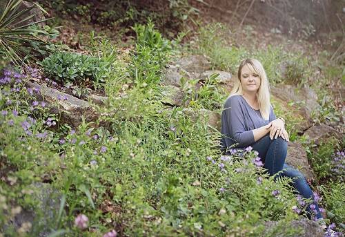 Donna Ray Norton sits in the grass on a rock-strewn hillside
