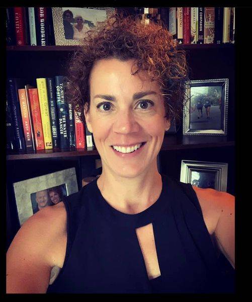 Dr. Heather Hawn, wearing a sleeveless top and posing in front of a bookcase.