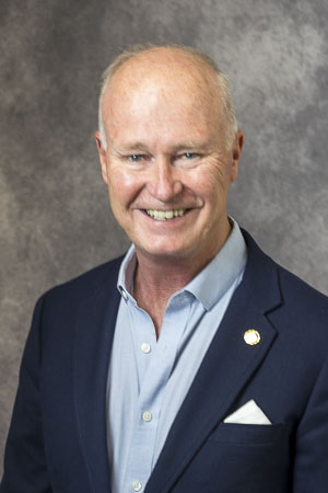 Robert McCarson, wearing a blue blazer with a white pocket square and open-collared shirt