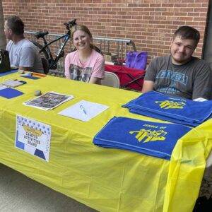 two students sit at Campus Activities Board table at College St Crawl