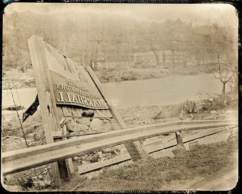 Tintype photo of French Broad River with a broken sign for Marshall after Hurricane Helene roared through