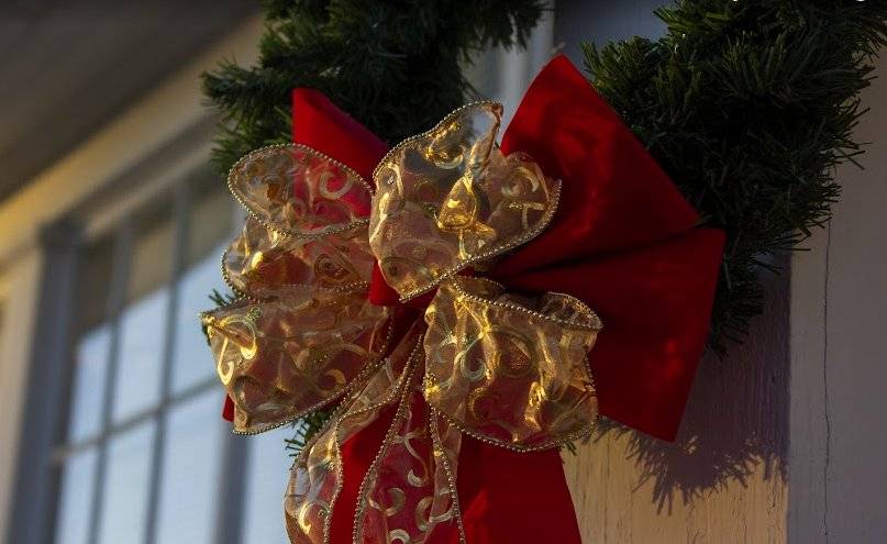 Red and gold ribbon on a wreath hanging outside a window.