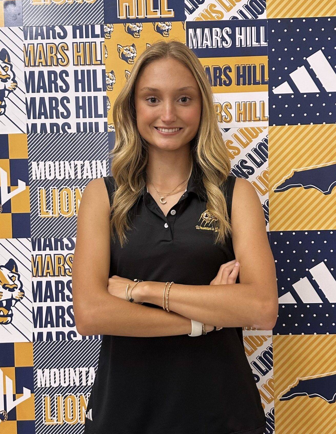 Caroline stands in front of MHU backdrop with logos