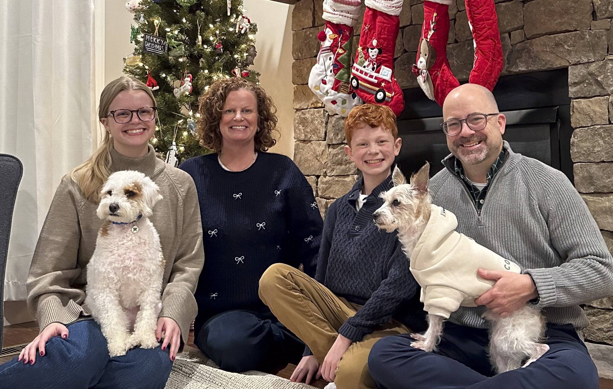 Parkinson / Long family at Christmas, seated on the floor in front of Christmas tree and stockings, with two white dogs. left to right: Abigail, Nichole, Adkins, Tracy